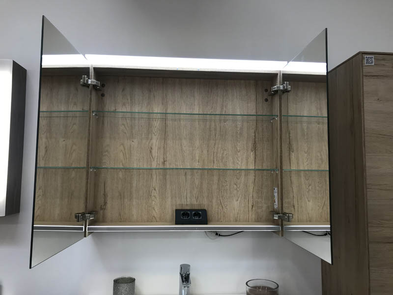 Detail beleuchteter Spiegelschrank Korpus in Holzoptik geöffnete Türen Innenansicht