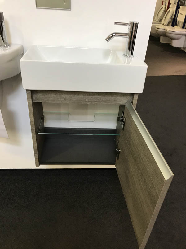 Bäderausstellung Ottenbruch kleines Handwaschbecken in weiß Armatur in Chrom geöffneter Unterschrank in Holzoptik