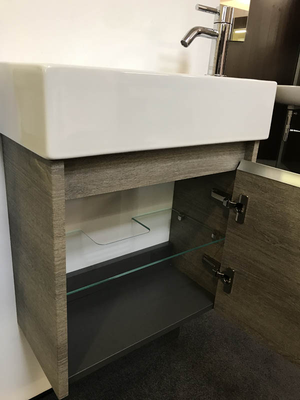 Bäderausstellung Ottenbruch kleines Handwaschbecken in weiß Armatur in Chrom geöffneter Unterschrank in Holzoptik
